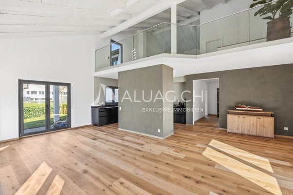 Grosser Salon mit offener Küche und Blick auf die Galerie mit sichtbaren Balken.