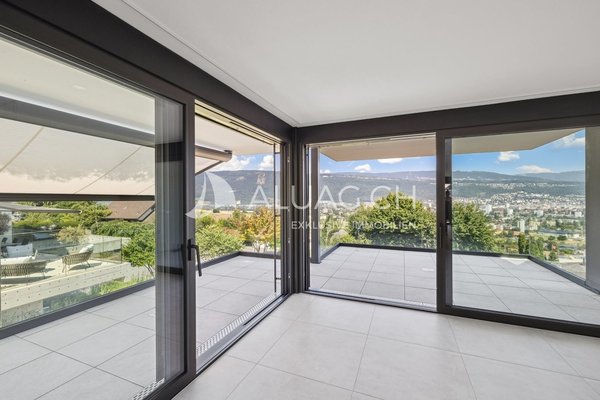 Grosszügige Terrasse mit Glasbrüstung, hochwertigem Plattenboden und Panoramablick ins Grüne