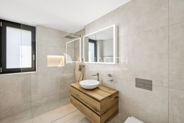 Modernes Bad mit Regendusche, Waschtisch in Holzoptik und beleuchtetem Spiegel  funktional und ästhetisch