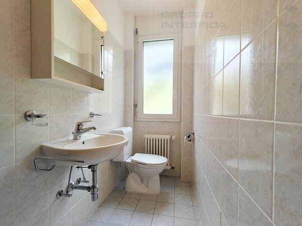 / a white bathroom with a sink, toilet, mirror, shower and window
