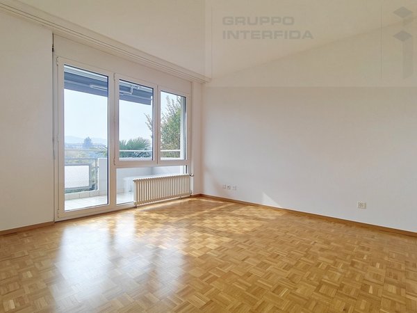 / an empty room with wooden floors and a large window overlooking a balcony