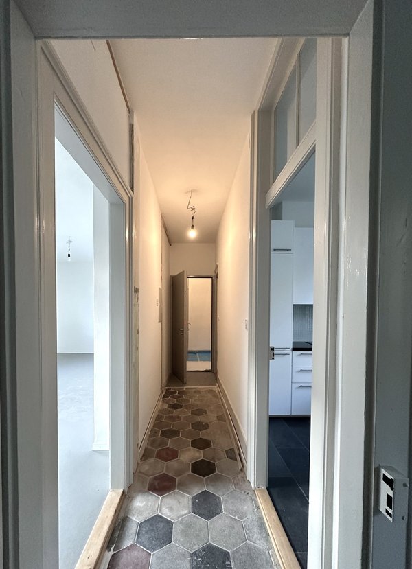 Corridor, dalles ciment d’origine, porte d’entrée isolante et serrure sécurisée multipoints, tableau fusibles logement, interphone entrée principale et 2 autres appartements, hauteur sous plafond