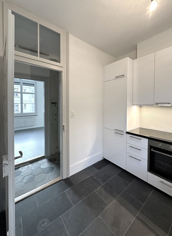 Cuisine, vue sur séjour:  grand frigo-congélateur, hotte extérieure, plaques induction, fenêtre 120x200cm triple vitrage, sol ardoise