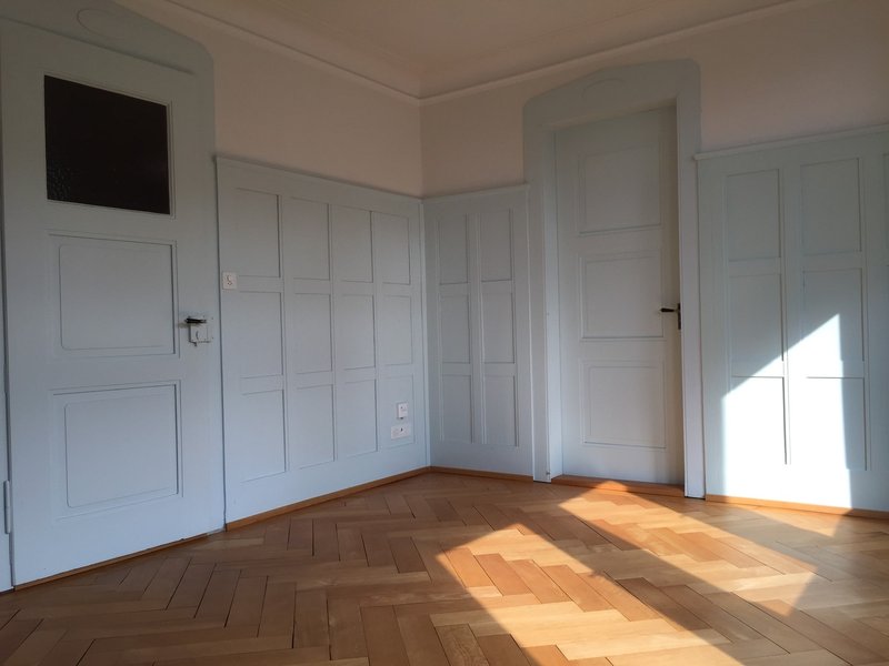 Wohnzimmer mit Kachelofen, Parkett und zwei Verbindungstüren