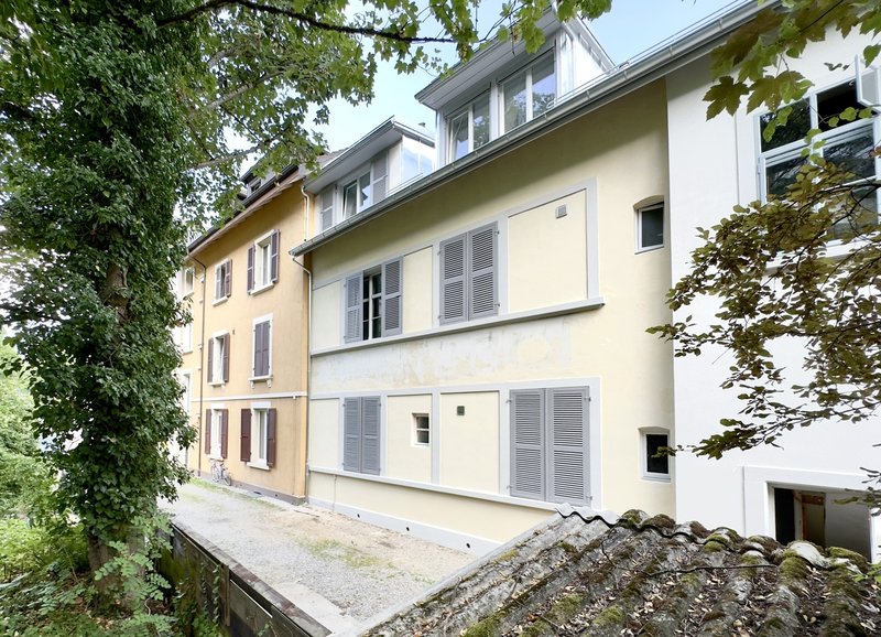 Impasse et façade Nord, entrée secondaire menant à la grande buanderie et caves privatives, et locaux techniques pompe à chaleur compteurs individuels