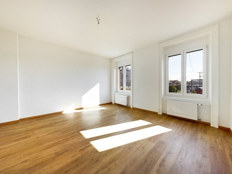 / an empty room with white walls and wooden floors and large windows