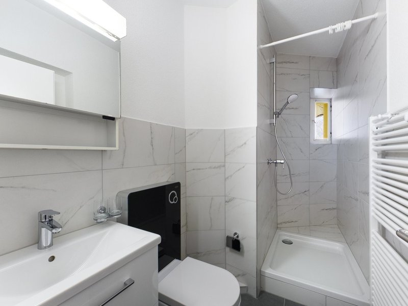 / a white bathroom with a sink, toilet and shower